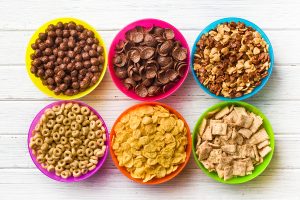 top view of various kids cereals in colorful bowls on wooden tab