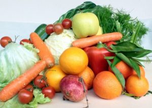A pile of fruits and vegetables (lettuce, carrots, oranges, apples, cherry tomatoes, etc.)