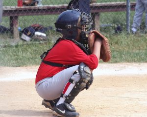 youth baseball player in catcher's uniform squatting in position