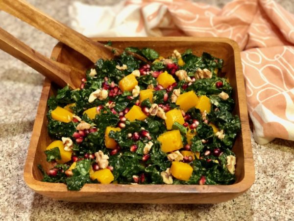 Kale, Butternut Squash and Pomegranate Salad in wooden bowl with utensils
